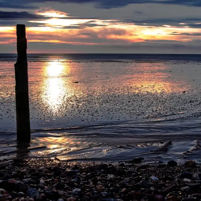 Voiliers amarrés dans un port au coucher du soleil, avec reflets sur l'eau