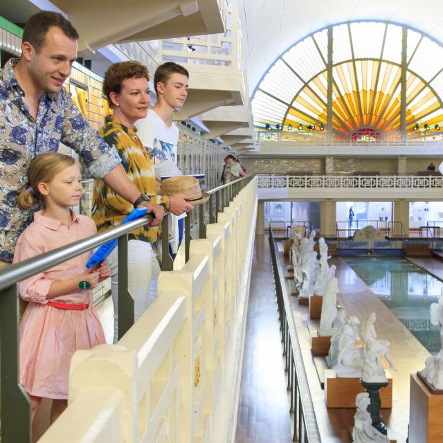 Noordfrankrijk_Roubaix_Musée La Piscine_Famille se promenant dans le musée_Vue sur le bassin et la galerie des statues © Hauts-de-France Tourisme_Anne-Sophie Flament