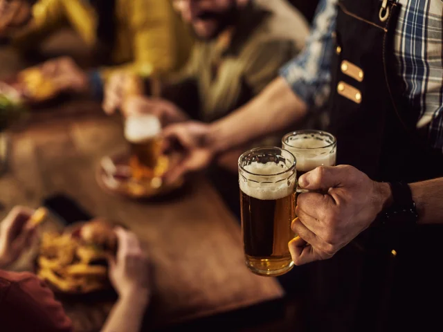 Close-up of waiter serving beer to customers in a pub.