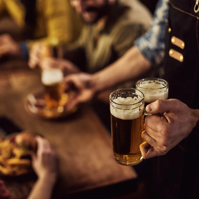 Close-up of waiter serving beer to customers in a pub.