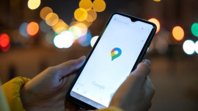 Ivano-Frankivsk, Ukraine - November 7, 2020: Close up of female hands holding mobile phone with Google maps navigation application at night city street.