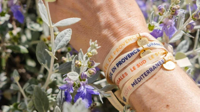 Mehrere Bänderarmbänder an einem Handgelenk in den Blumen