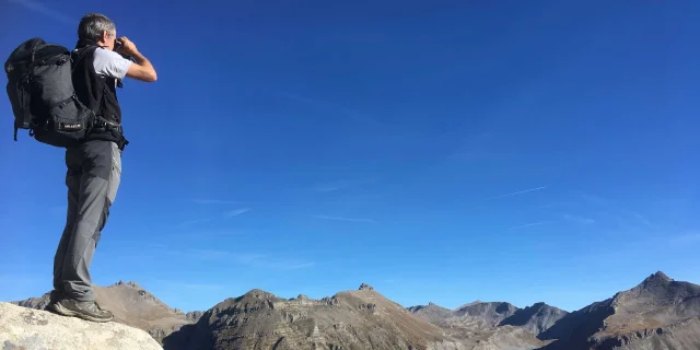 Un randonneur qui observe le panorama du Mercantour avec des jumelles