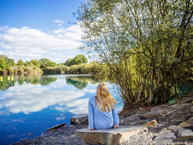 Femme assise au bord d'un plan d'eau des Ardoisières
