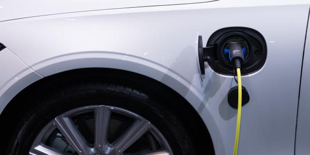 Plan rapproché sur la prise de recharge sur un véhicule électrique blanc en cours de charge