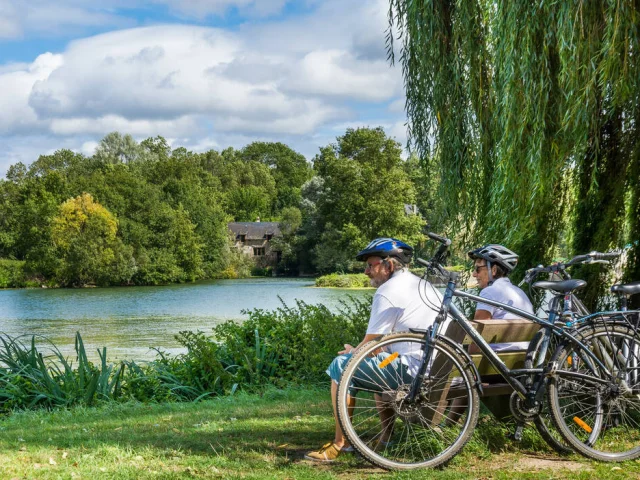 Cyclistes assis sur un banc au bord du Loir à Villevêque