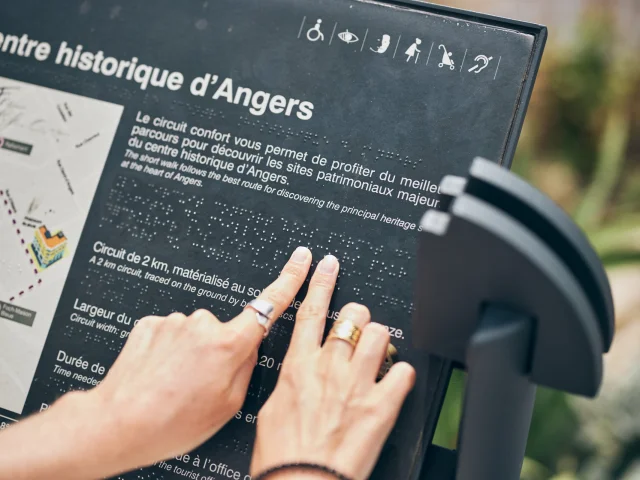 Mains sur le texte braille d'un lutrin patrimonial