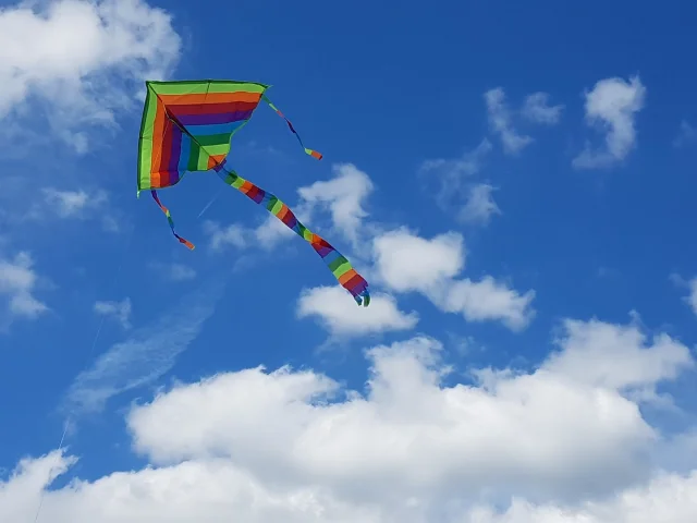 Cerf-volant triangulaire multicolore volant dans un ciel bleu