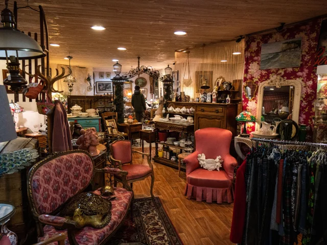 Intérieur de La Malle Aux Trouvailles avec plusieurs décoration comme des fauteuils, vêtements