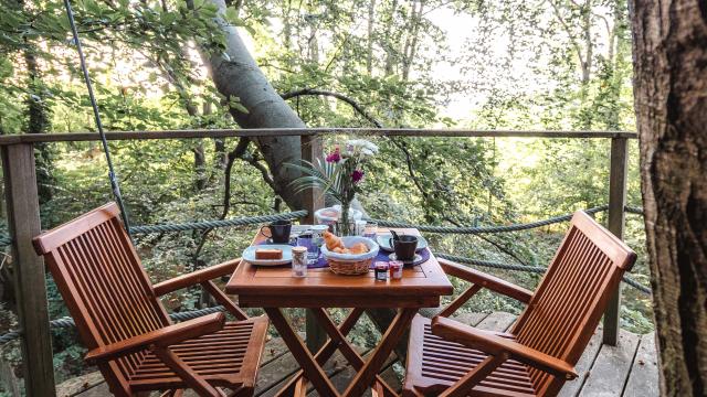 Table avec petit déjeuner sur un balcon d'une cabane dans les arbres en forêt