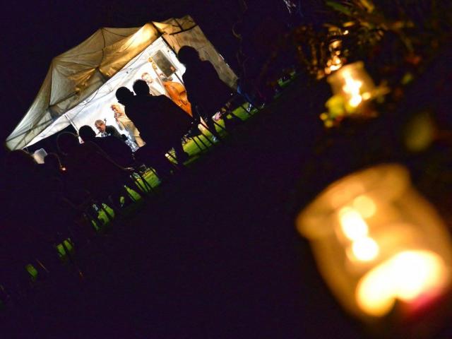 Personne écoutant un concert devant une tente, de nuit éclairé à la bougie