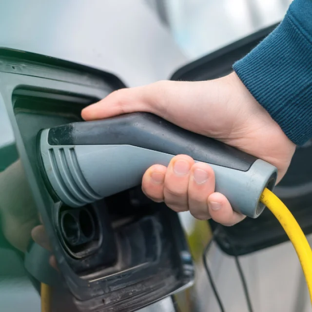 Très gros plan sur une main prenant un câble de recharge pour voiture électrique grise