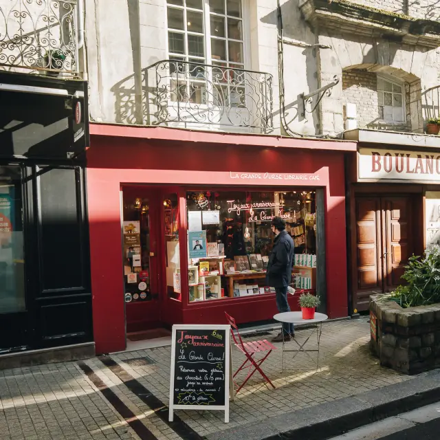 Vitrine rouge de la librairie. Petite table de jardin devant.