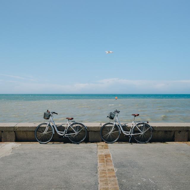 2 vélos poser sur le parapet du front de mer de Dieppe devant une mer et un ciel bleus