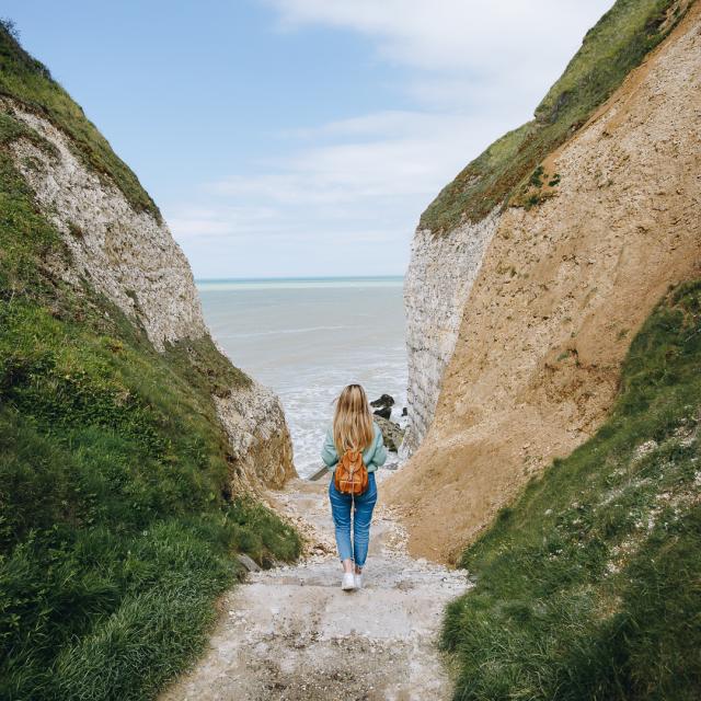 Jeune femme descendant le chemin entre les valleuses (passage entre deux falaises)