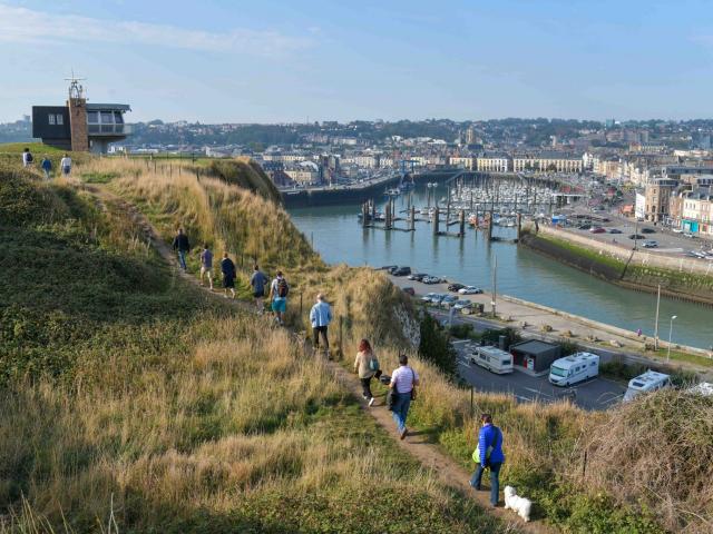 Groupe de personnes cheminant sur un sentier de falaise au-dessus du port de Dieppe