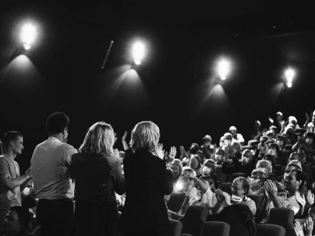 Artistes de dos sur une scène face à un public qui applaudit