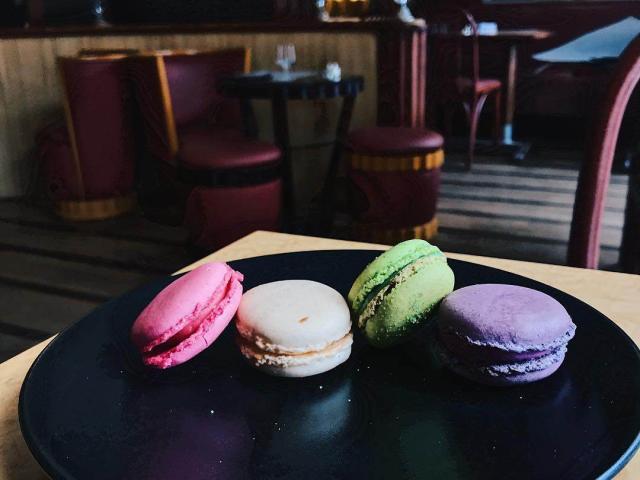4 macarons (rose, blanc, vert et violet) dans une assiette noire dans le salon de thé Divernet de Dieppe