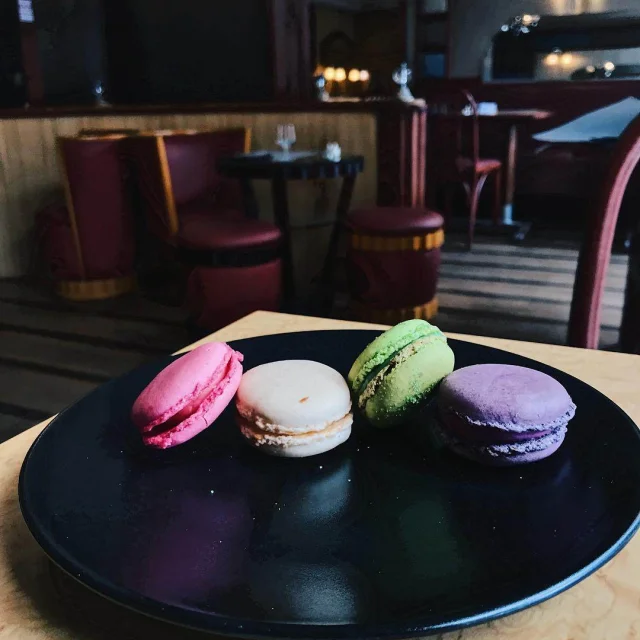 4 macarons (rose, blanc, vert et violet) dans une assiette noire dans le salon de thé Divernet de Dieppe