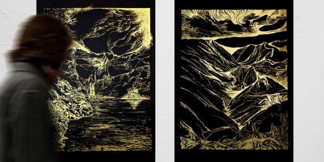Un visiteur devant 2 pyrogravures représentant des paysages de montagnes stylisés
