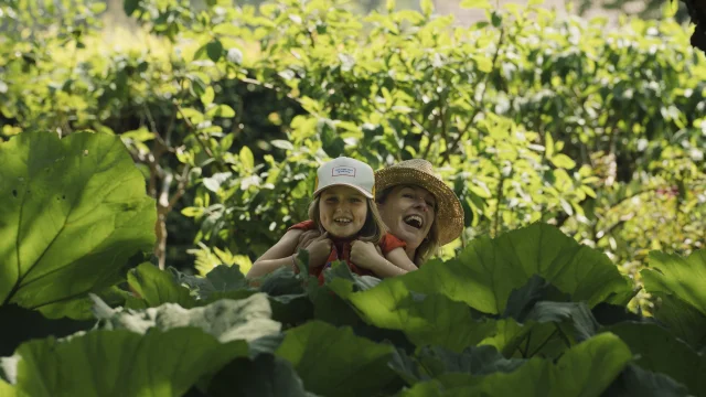 Une maman et sa fille émergent d'une cachette au milieu de plantes géantes