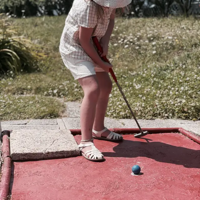 Jeune fille tenant un club de golf devant une balle s'apprêtant à tirer