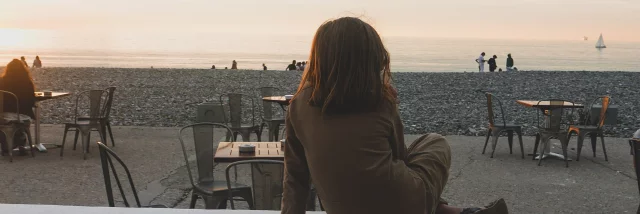 Jeune fille regardant le coucher du soleil sur les murets devant la mer de Dieppe