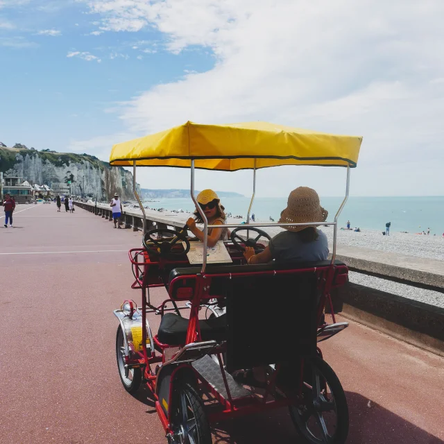 2 petites filles avec des chapeaux à bord d'une rosalie, voiturette à pédale, le long de l'esplanade de Dieppe, face aux falaises et à la mer