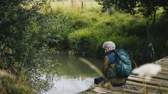 Une homme pêche dans la rivière, assis sur un ponton, dans la campagne de Sainte-Marguerite-sur-Mer