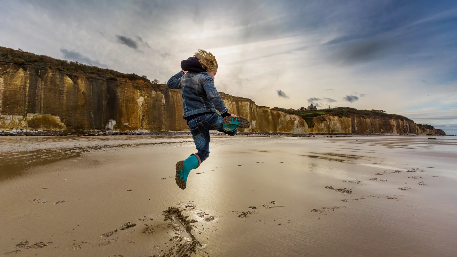 Un enfant saute sur la plage de Varengeville à marée basse devant les falaises