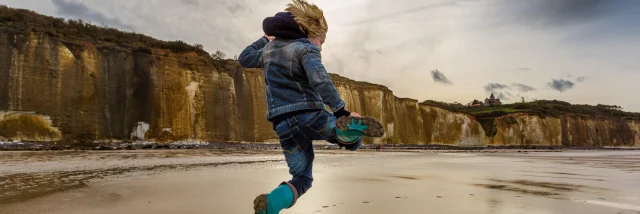 Un enfant saute sur la plage de Varengeville à marée basse devant les falaises