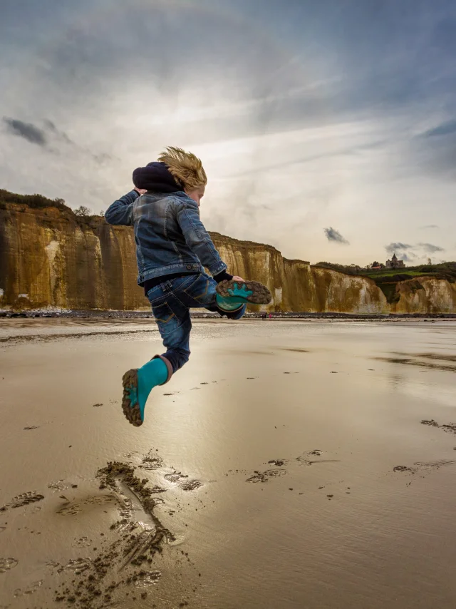 Un enfant saute sur la plage de Varengeville à marée basse devant les falaises