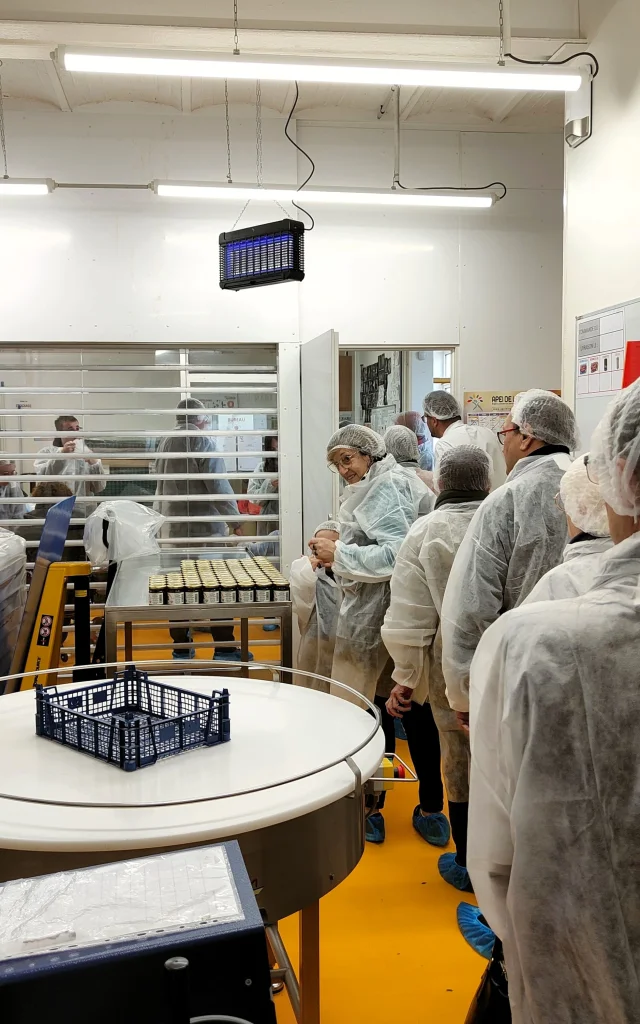 Un groupe de personnes équipées de charlottes et de vêtements de protection dans l'une des salles de conception du caramel de pommes dieppois