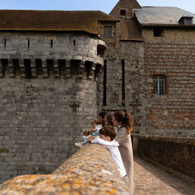 Une famille explore les abords du Château-Musée de Dieppe, perchée sur la falaise avec vue sur la mer.
