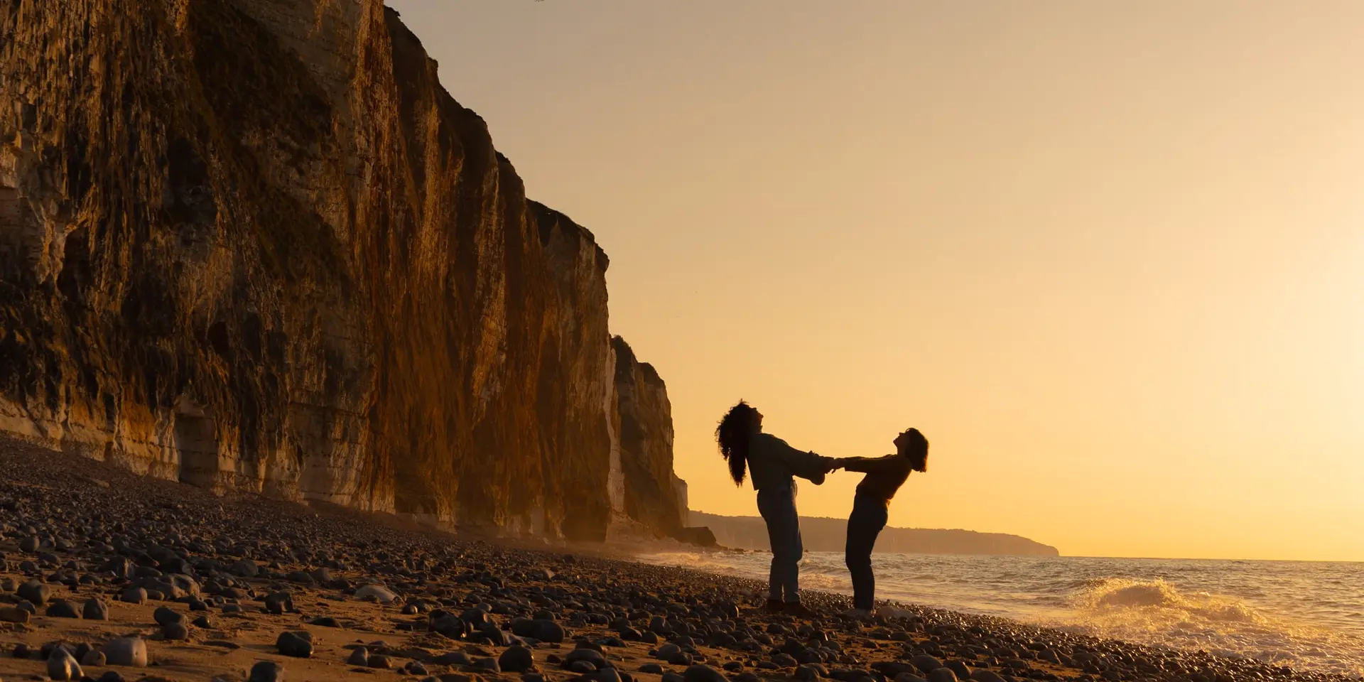 Ambiance paisible sur la plage de Dieppe, baignée d’une lumière orangée en fin de journée.