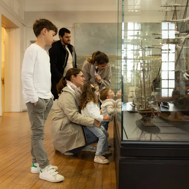 Une famille regarde une vitrine du musée