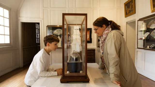 Un petit garçon et une jeune femme de chaque bôté d'un vitrine présentant des ivoires au musée