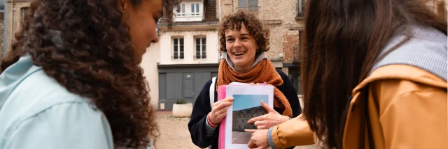 Une guide souriante montre une photo d’archive à deux participantes lors d’une visite commentée dans le centre historique de Dieppe.