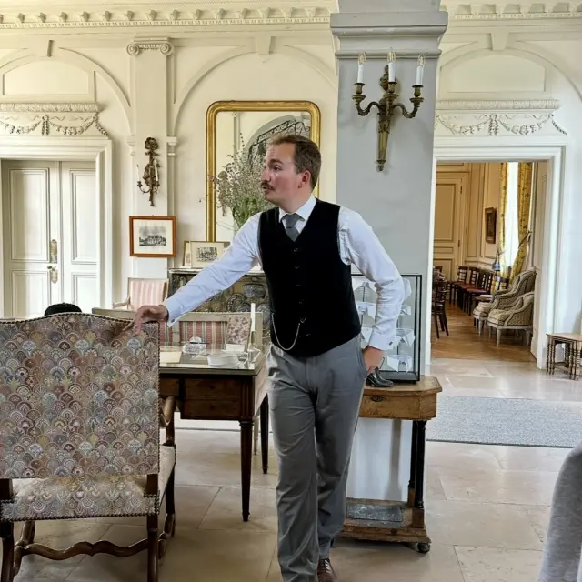 Guide en costume d’époque présentant une salle du château de Miromesnil lors d’une visite en groupe