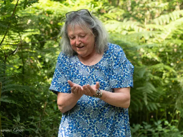 Conteuse devant des fougères regardant ses mains