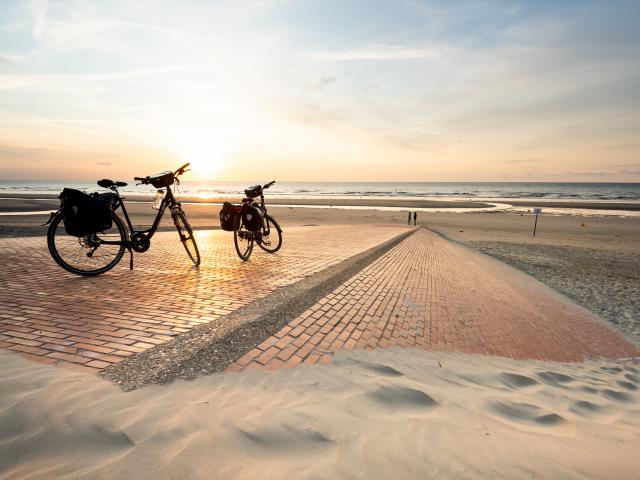 Vélos sur la dige de Leffrinckoucke au soleil couchant.