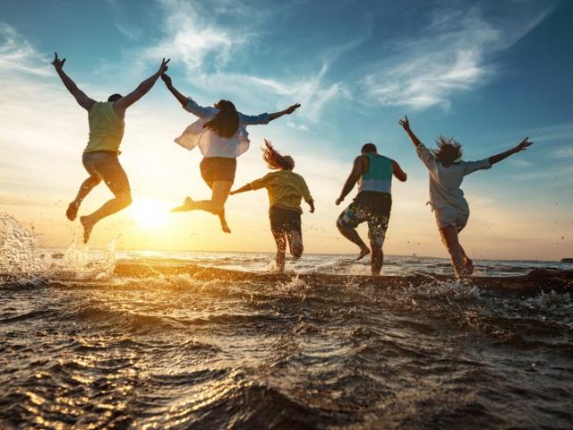 Five happy friends run and jump to sunset lake beach after party
