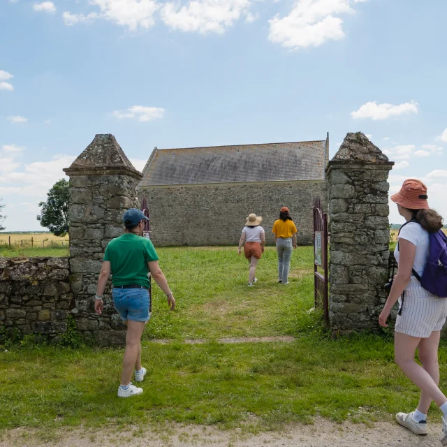 Visiteurs franchissant le portail d'entrée. La Chapelle de Rohars est en arrière-plan.