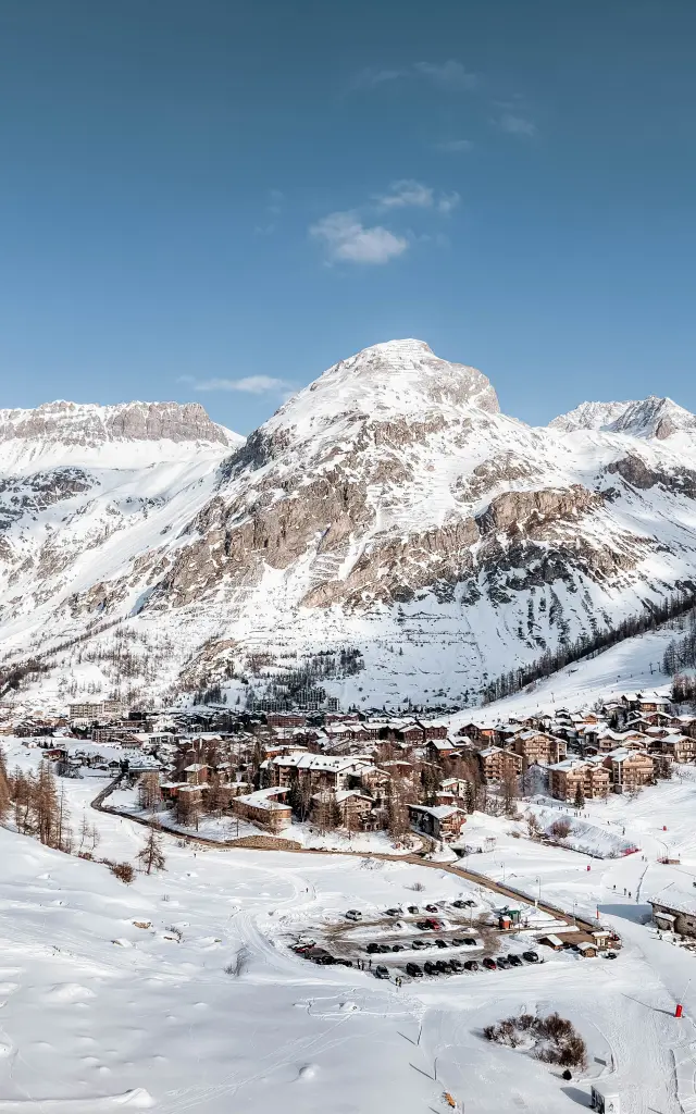 Vue d'une station de ski enneigée avec des pistes et des remontées mécaniques sous un ciel bleu dégagé
