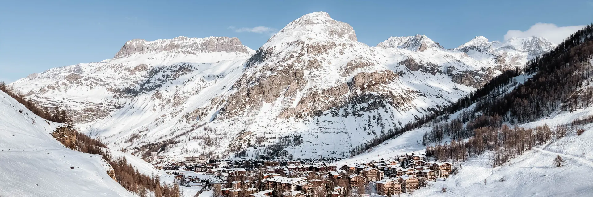 Vue d'une station de ski enneigée avec des pistes et des remontées mécaniques sous un ciel bleu dégagé