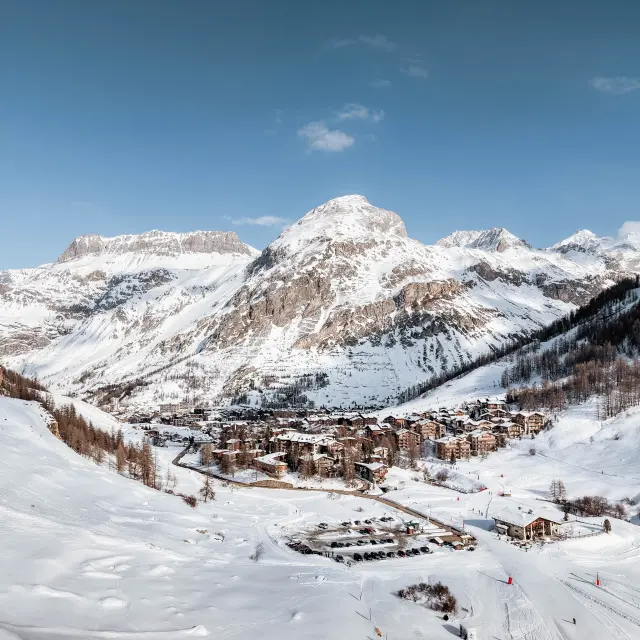 Vue d'une station de ski enneigée avec des pistes et des remontées mécaniques sous un ciel bleu dégagé