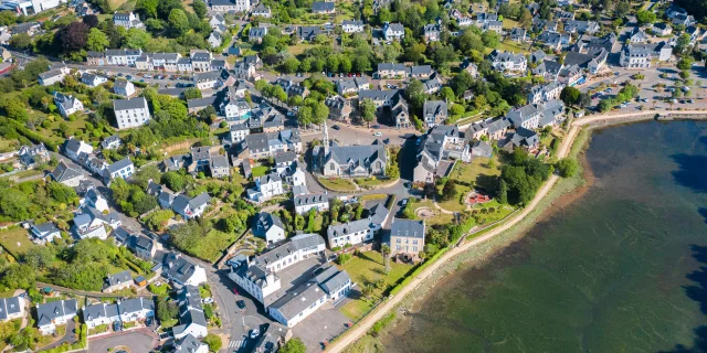 Vue aérienne de l'église Notre Dame Izel Vor et du bourg de La Forêt comprenant des maisons et une partie de l'anse de La Forêt