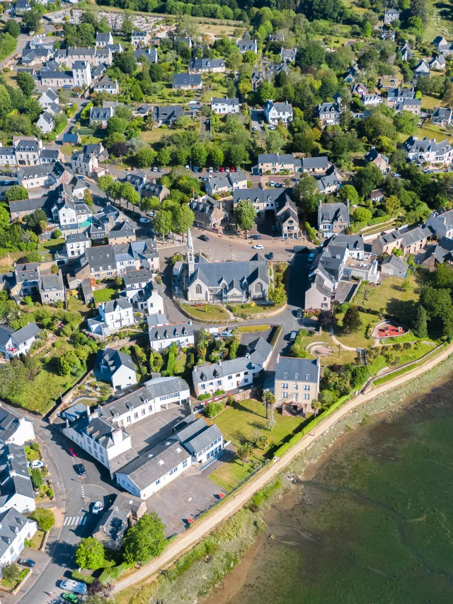 Vue aérienne de l'église Notre Dame Izel Vor et du bourg de La Forêt comprenant des maisons et une partie de l'anse de La Forêt