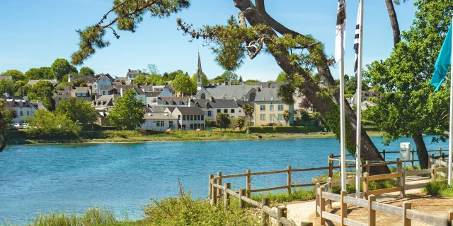 View of the La Forêt cove at high tide with the coastal path and the town of La Forêt-Fouesnant