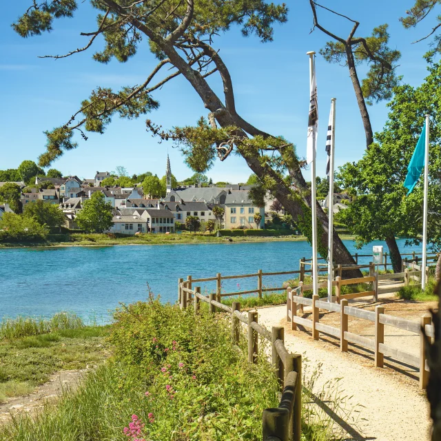 View of the La Forêt cove at high tide with the coastal path and the town of La Forêt-Fouesnant